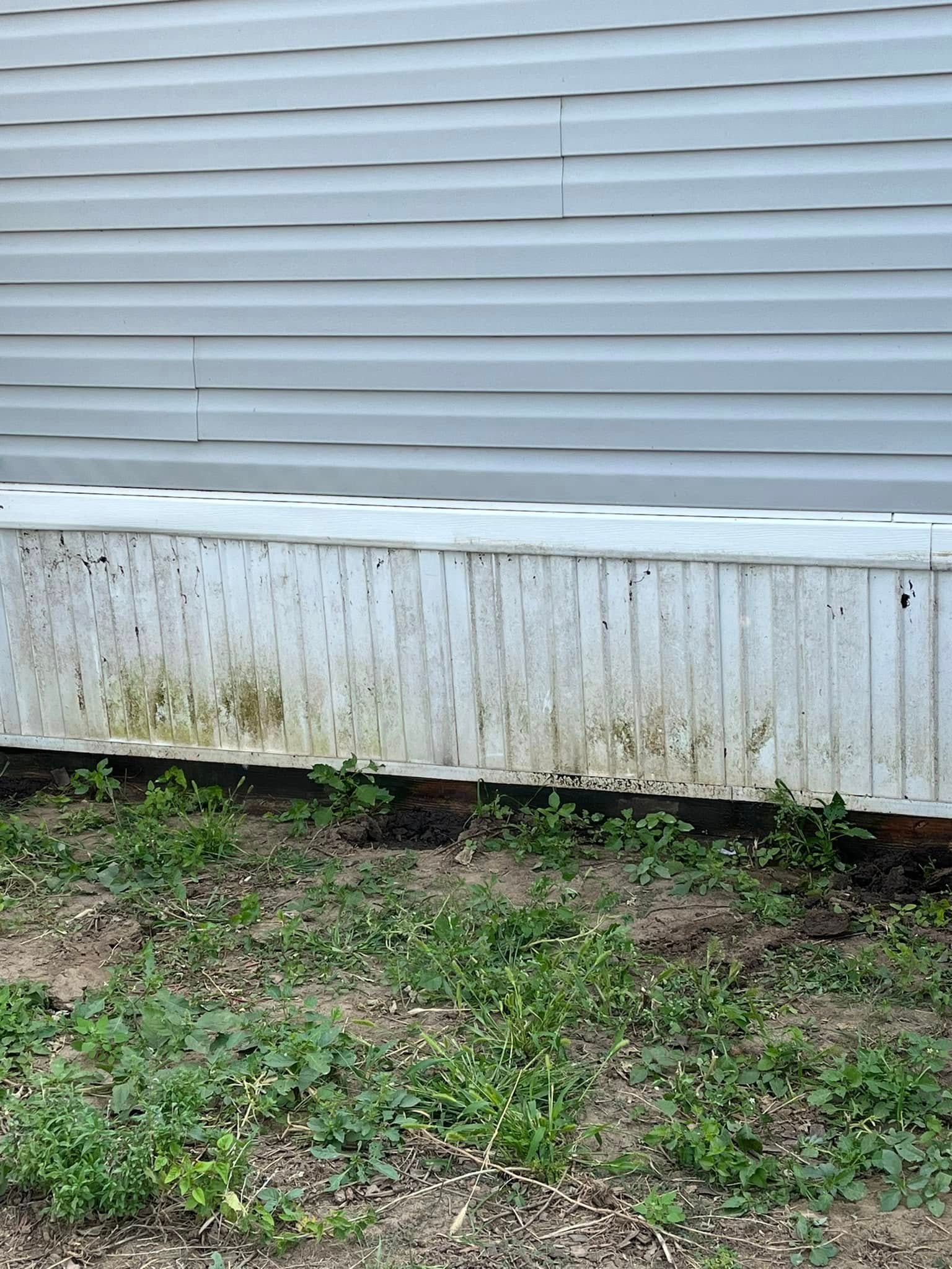 A white planter is sitting in the grass in front of a house.