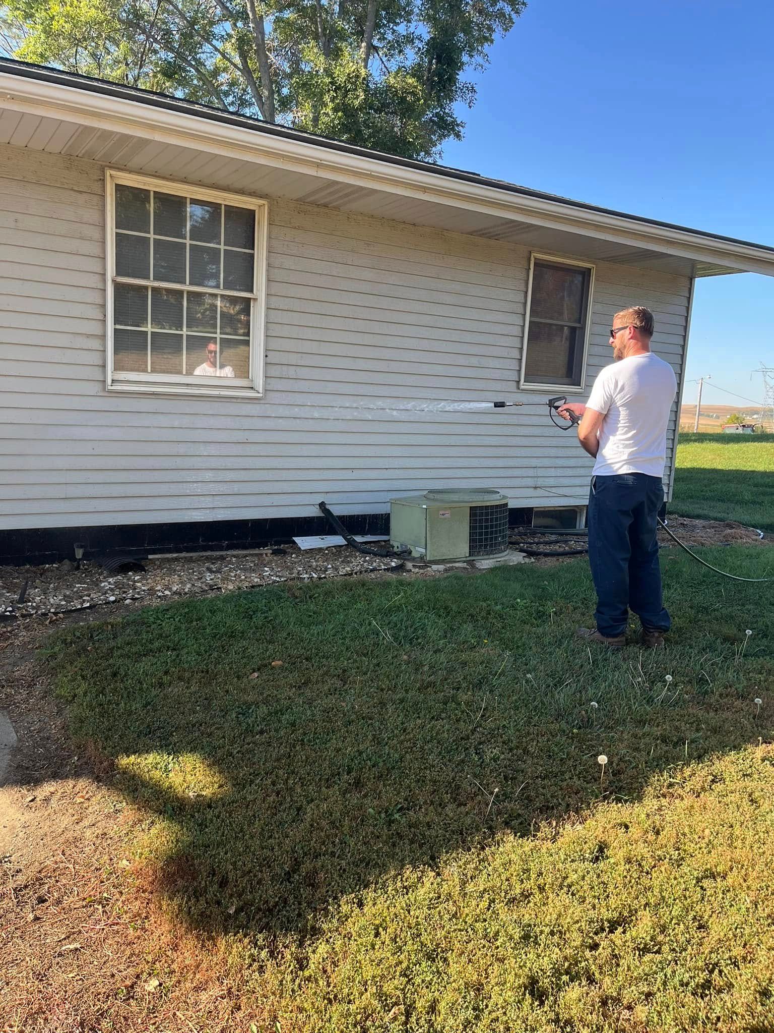 A man is spraying a house with a hose.