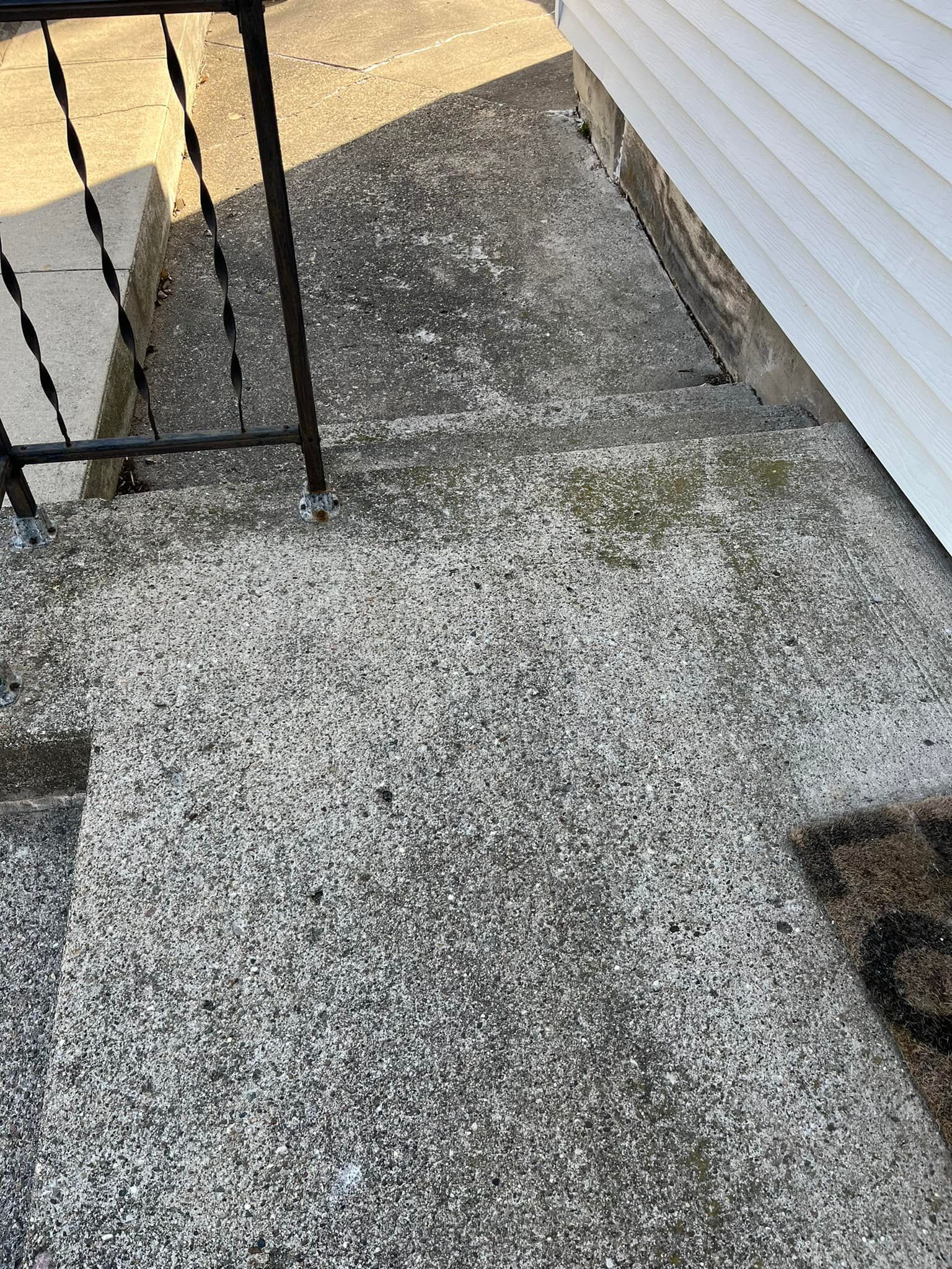 A concrete walkway with stairs leading up to a house.