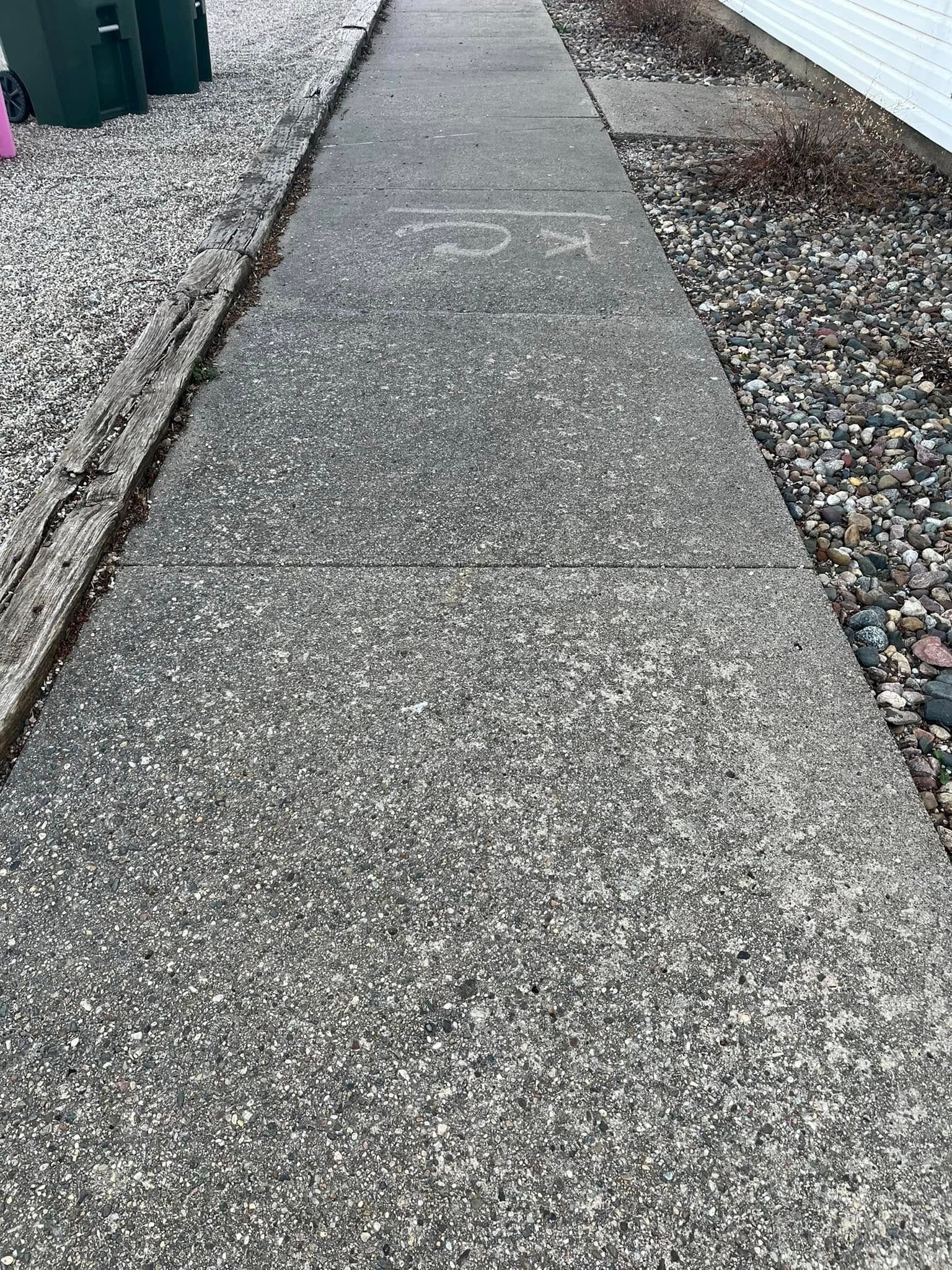 A concrete sidewalk with gravel on the side of it.