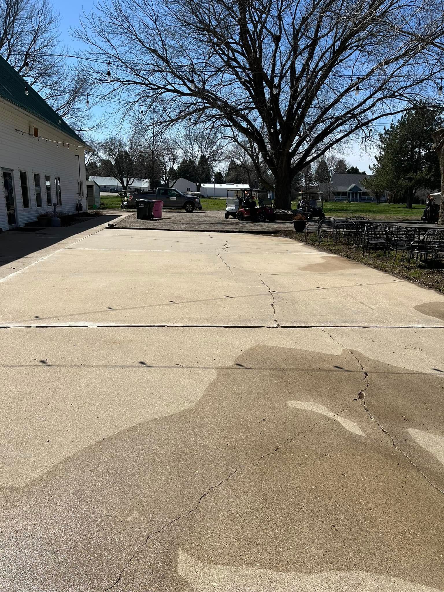 A concrete driveway with a tree in the background and a building in the background.