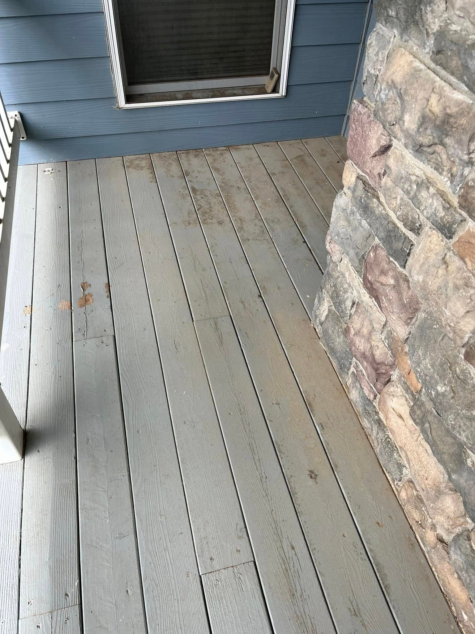 A wooden deck with a stone wall in the background.