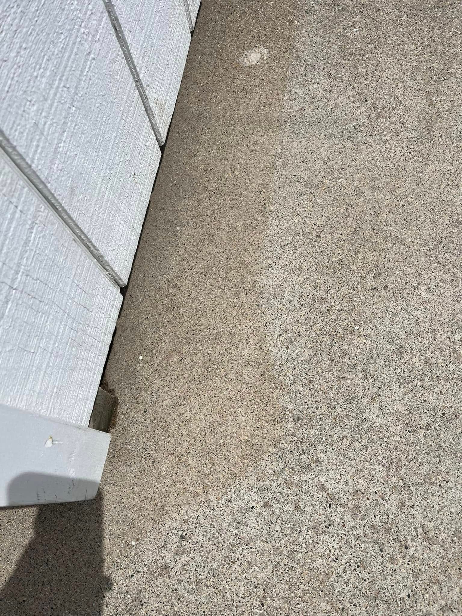 A close up of a concrete floor with a white fence in the background.
