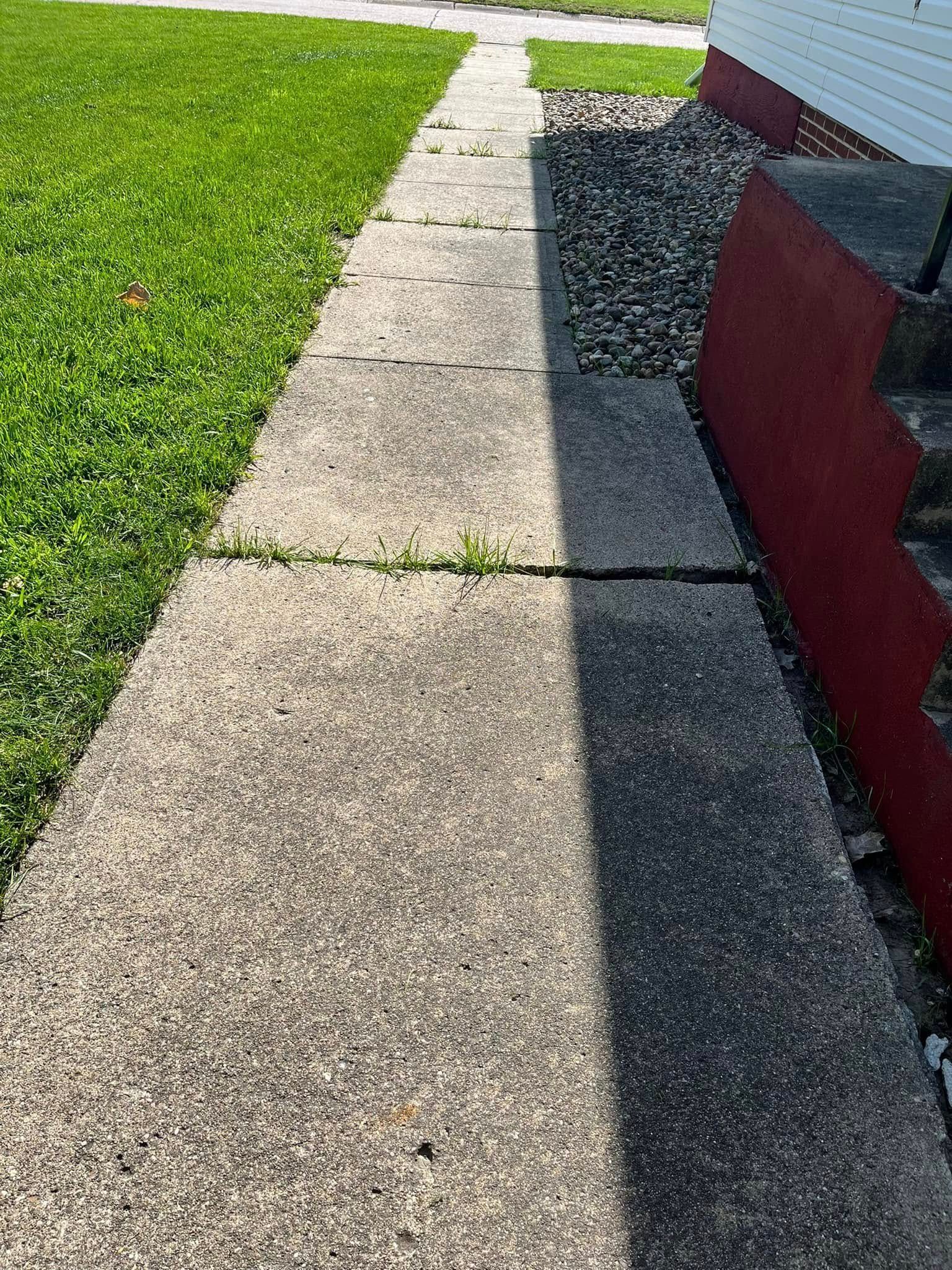 A sidewalk leading to a house with grass on the side of it.