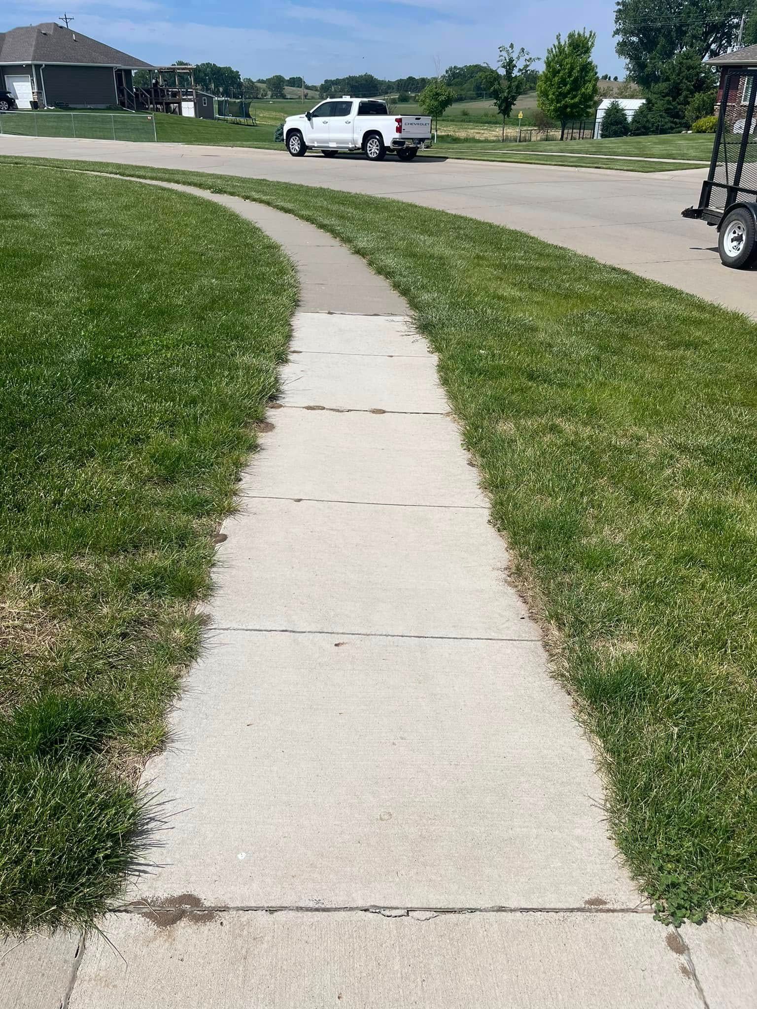 A white truck is parked on the side of the road next to a sidewalk.