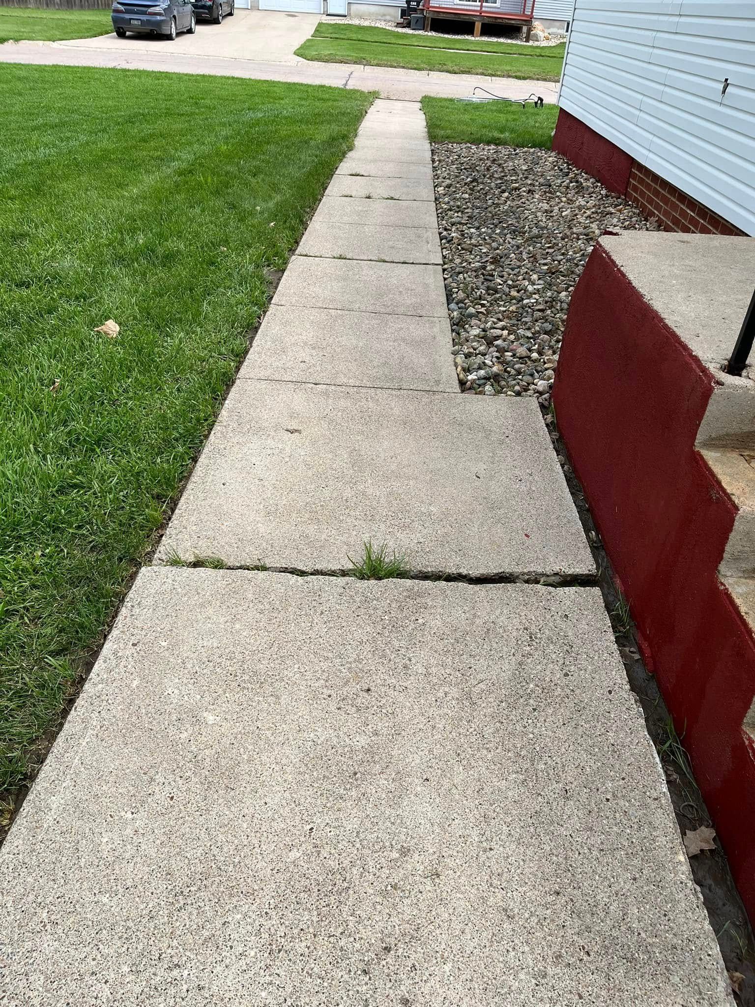 A sidewalk leading to a house with a car parked on the side of it.