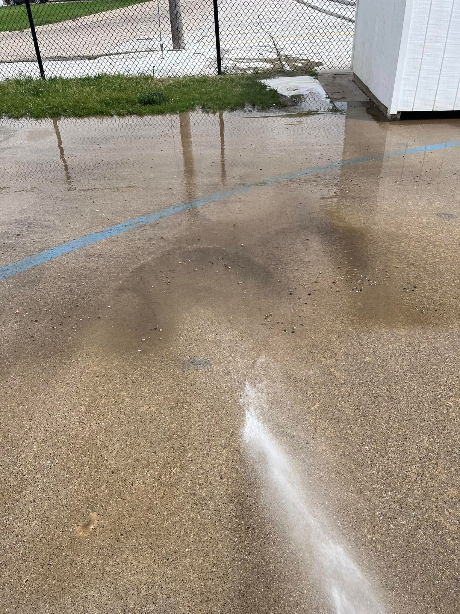 A person is spraying water on a concrete floor.
