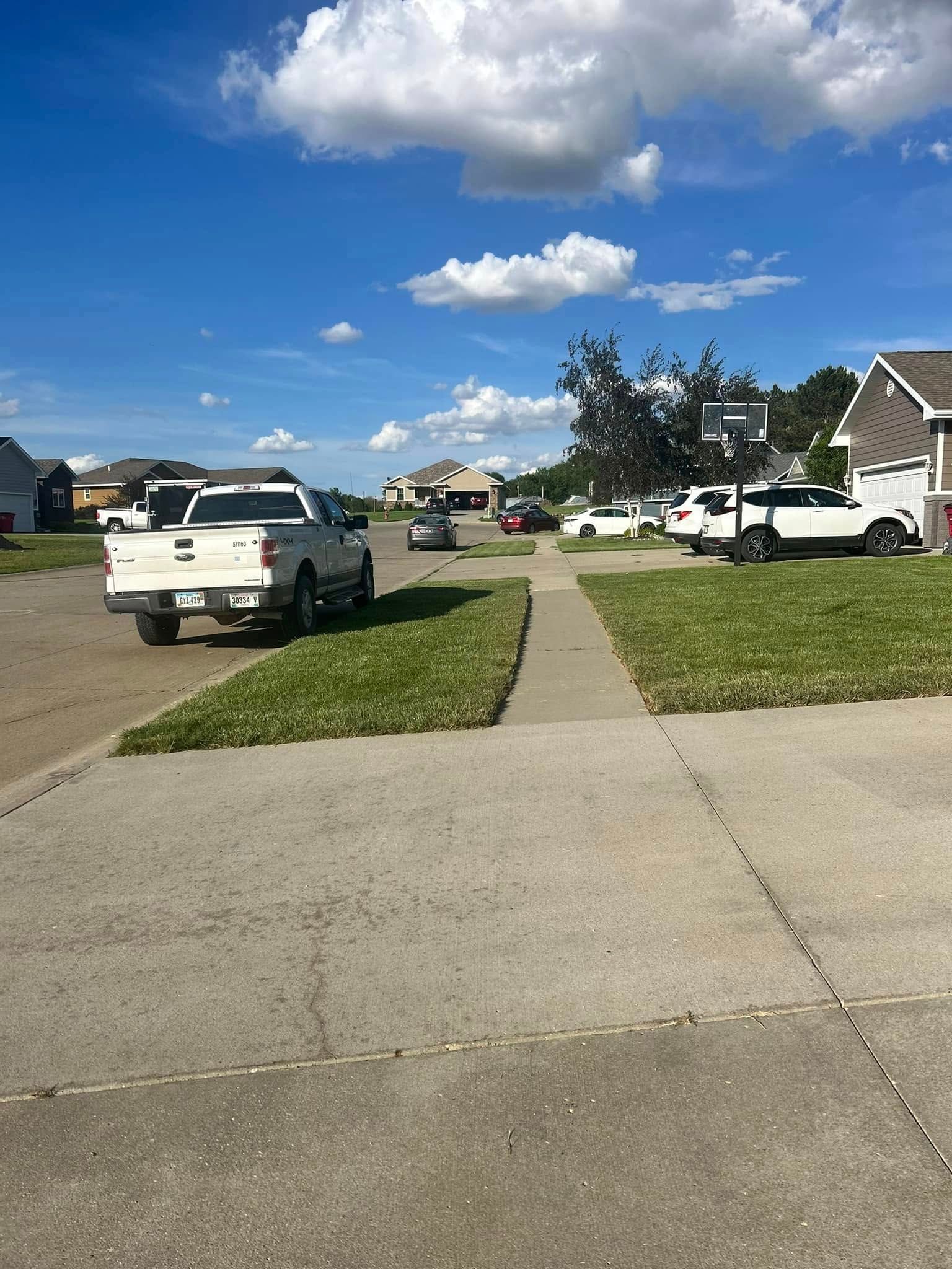 A white truck is parked on the side of the road next to a basketball hoop.