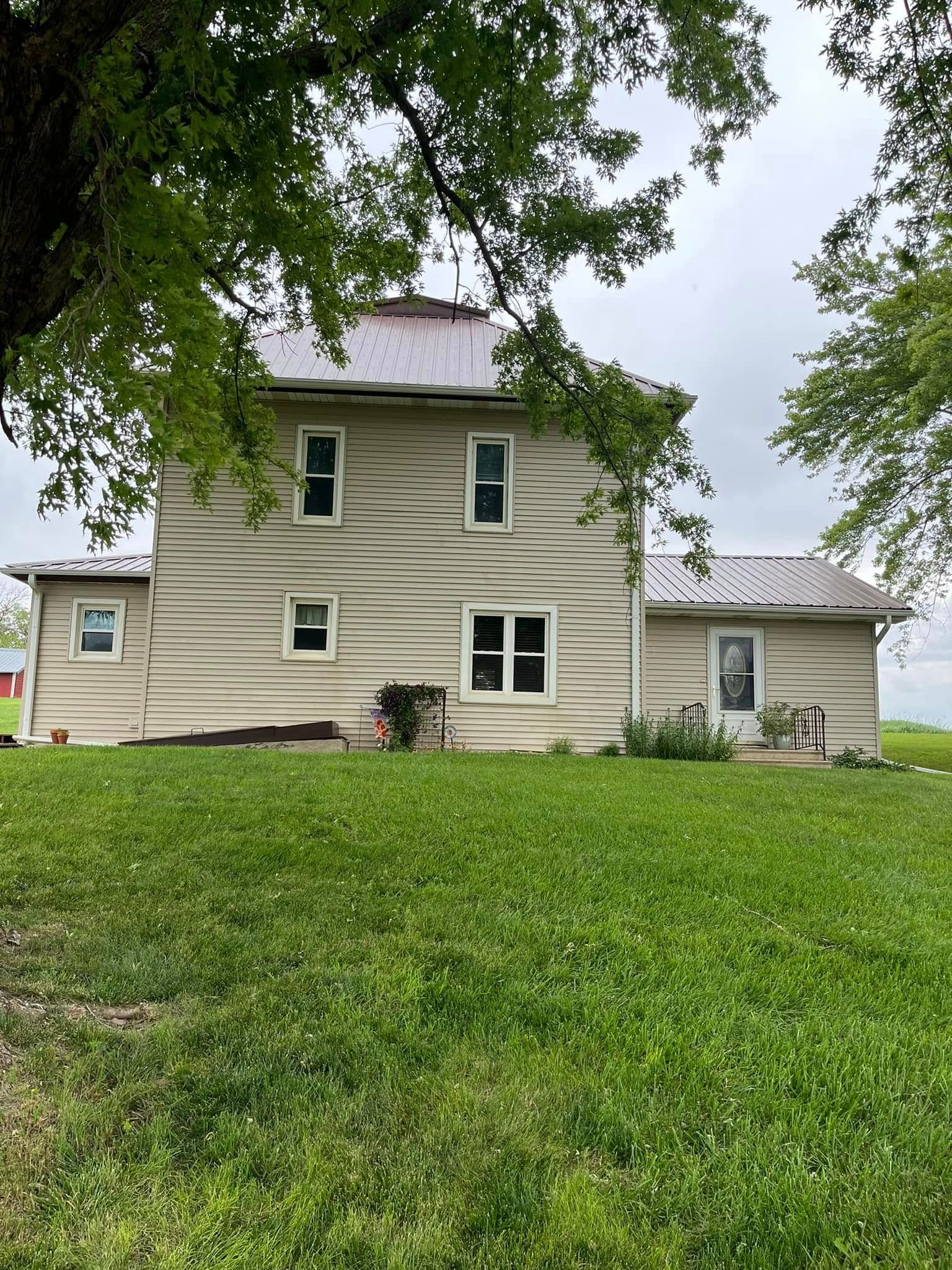 A large house with a lot of windows is sitting on top of a lush green field.