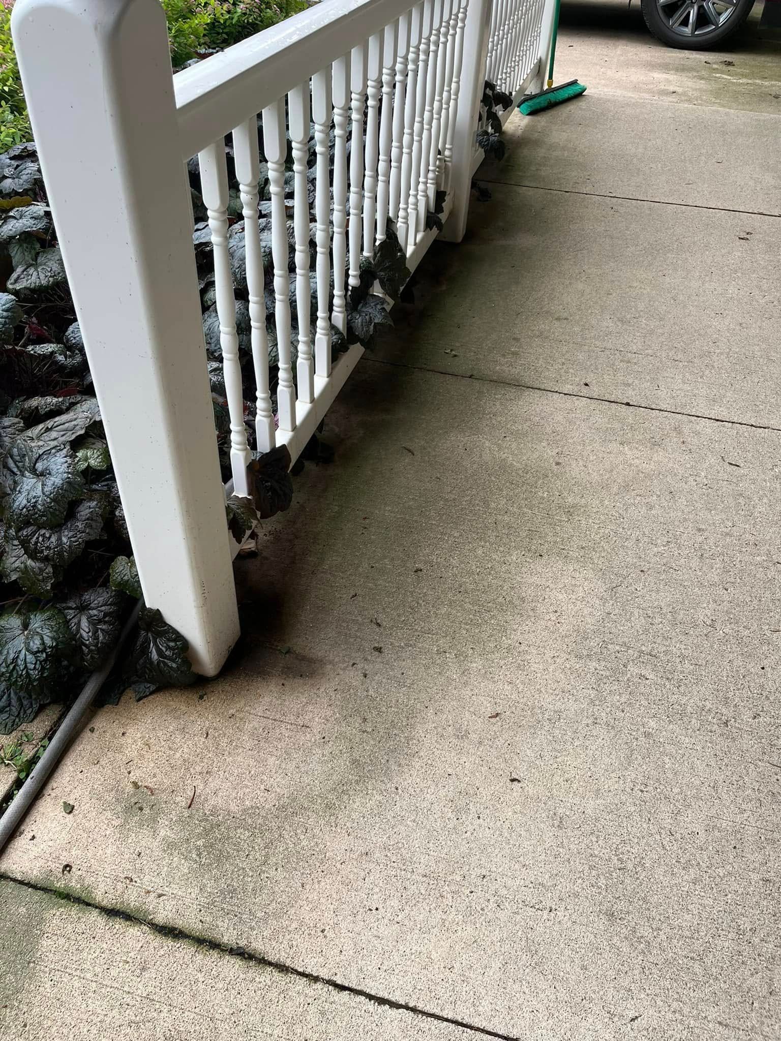 A white fence is sitting on top of a concrete porch.