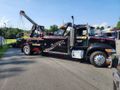 A black tow truck is parked on the side of the road.