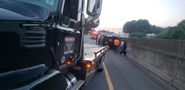 A tow truck is towing a car on the side of a highway.