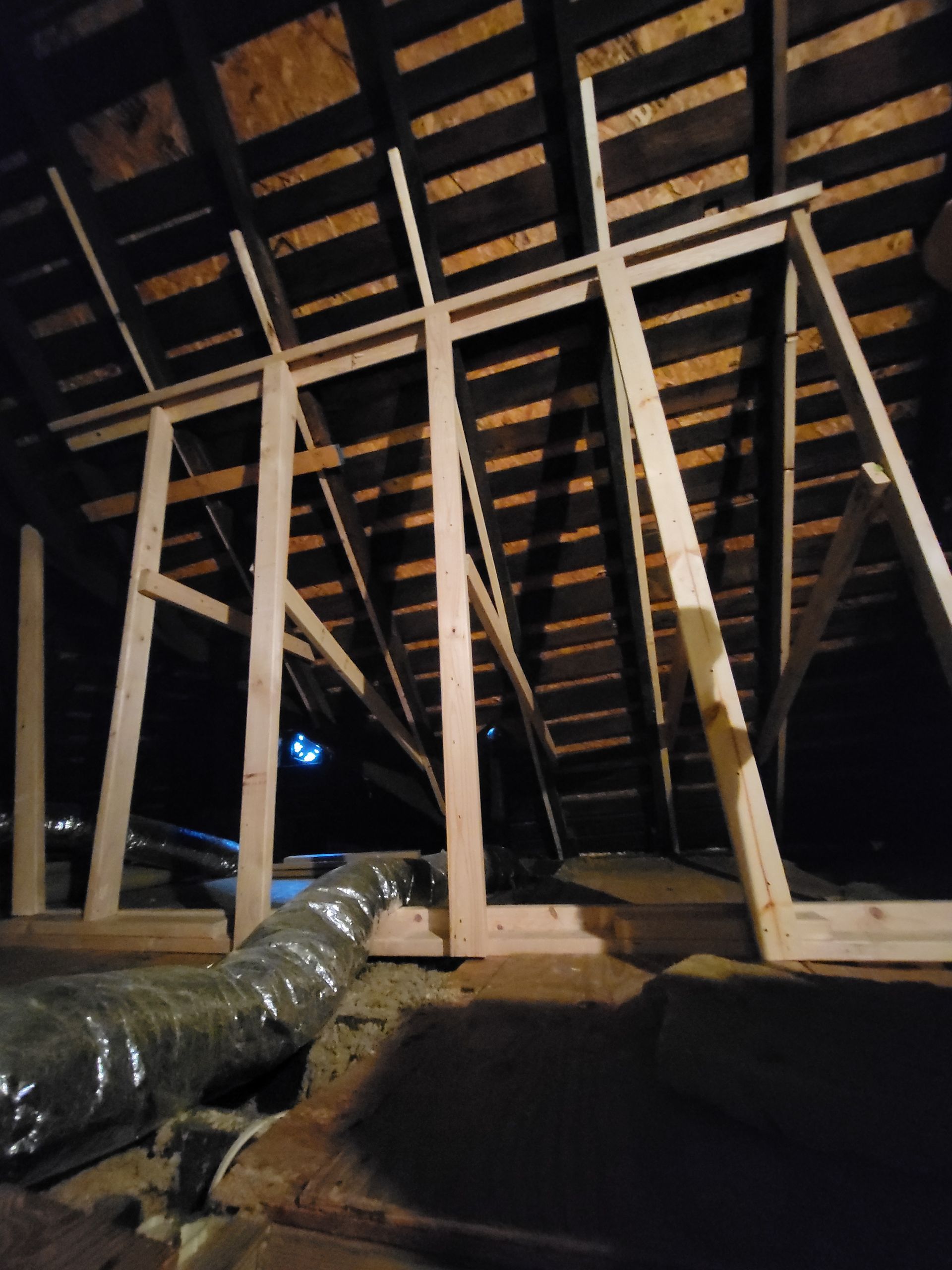 A wooden structure is being built in the attic of a house