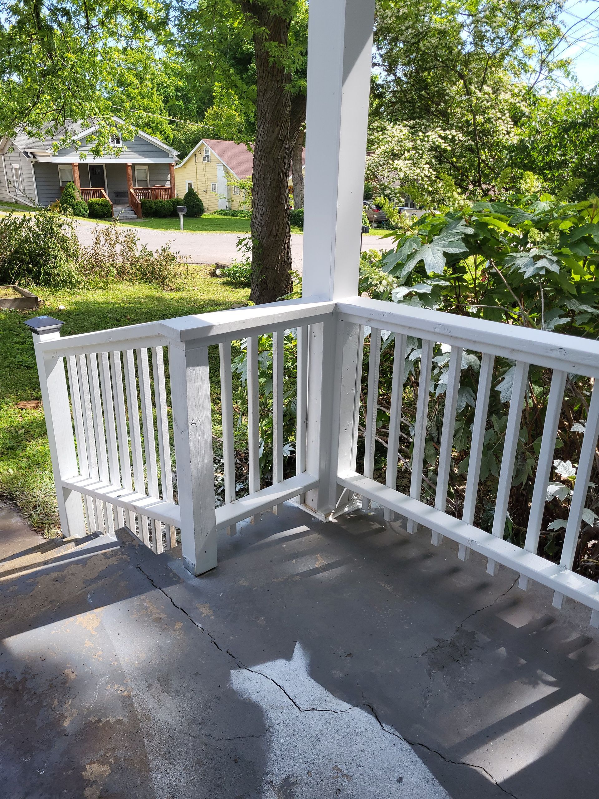 A white dog is standing on a porch with a white railing.