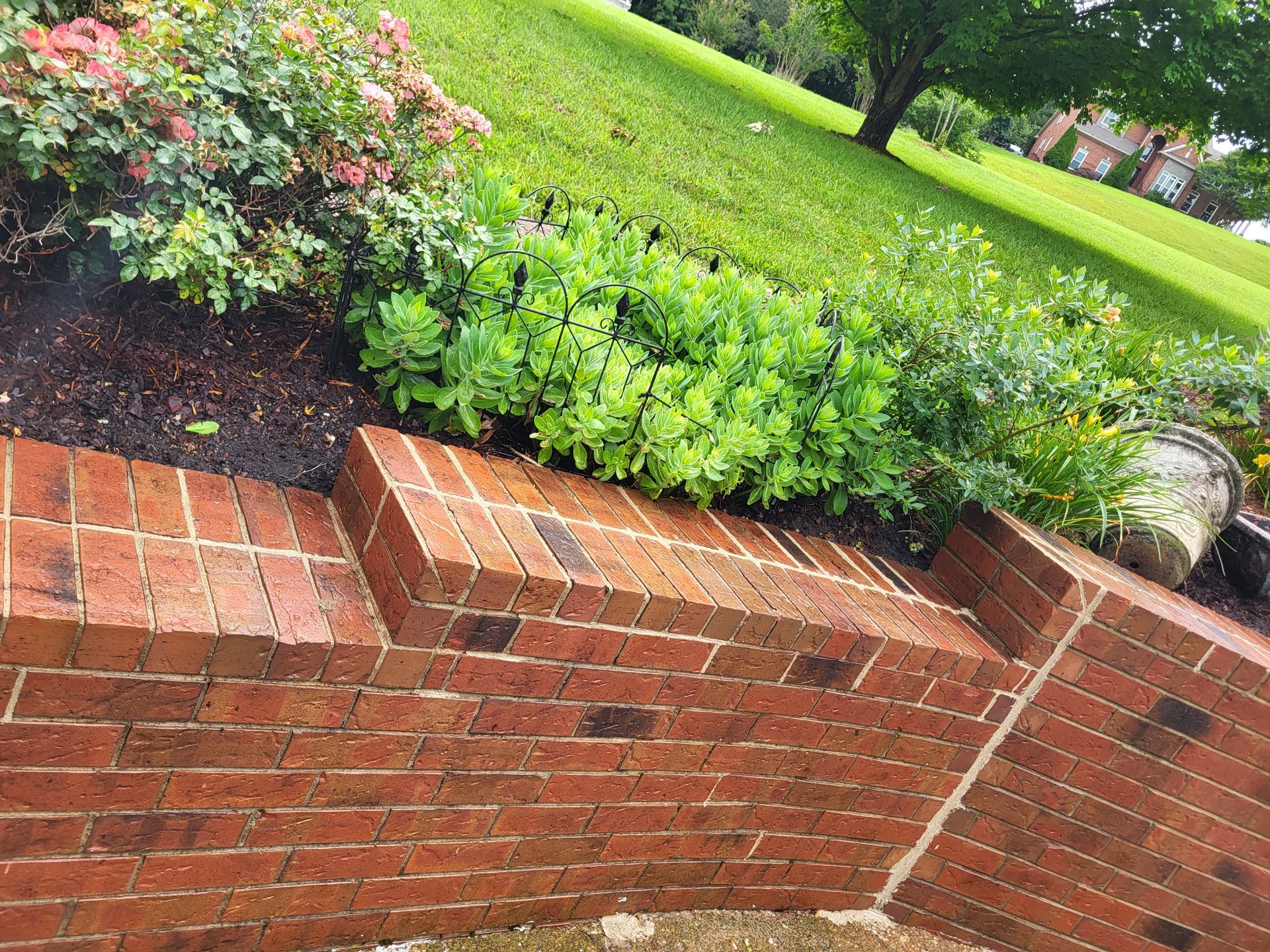 A brick wall with steps leading up to a grassy hillside.