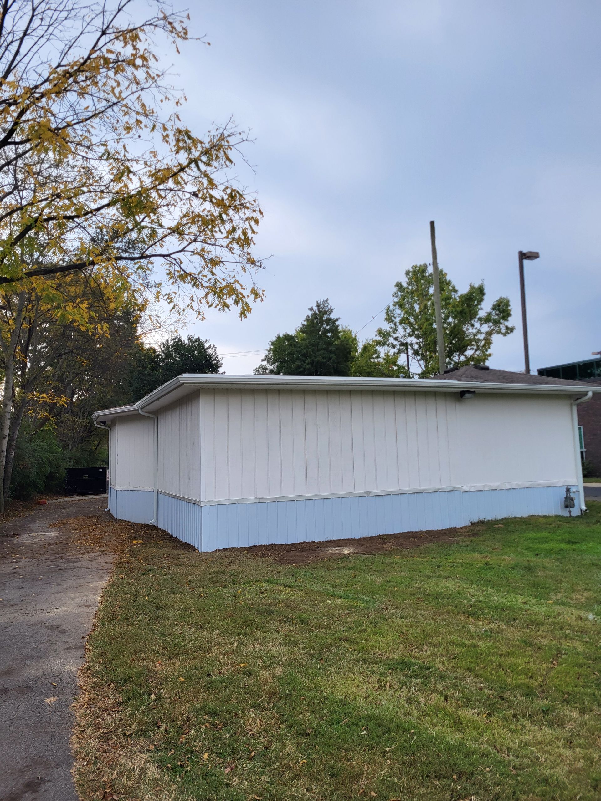 A white house with blue trim is sitting on top of a lush green field.