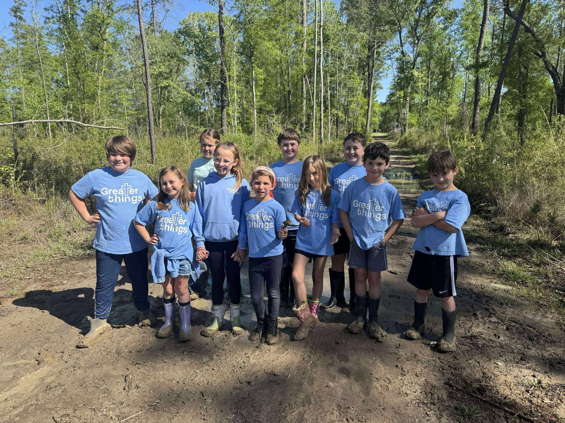 A group of children are posing for a picture in the woods.
