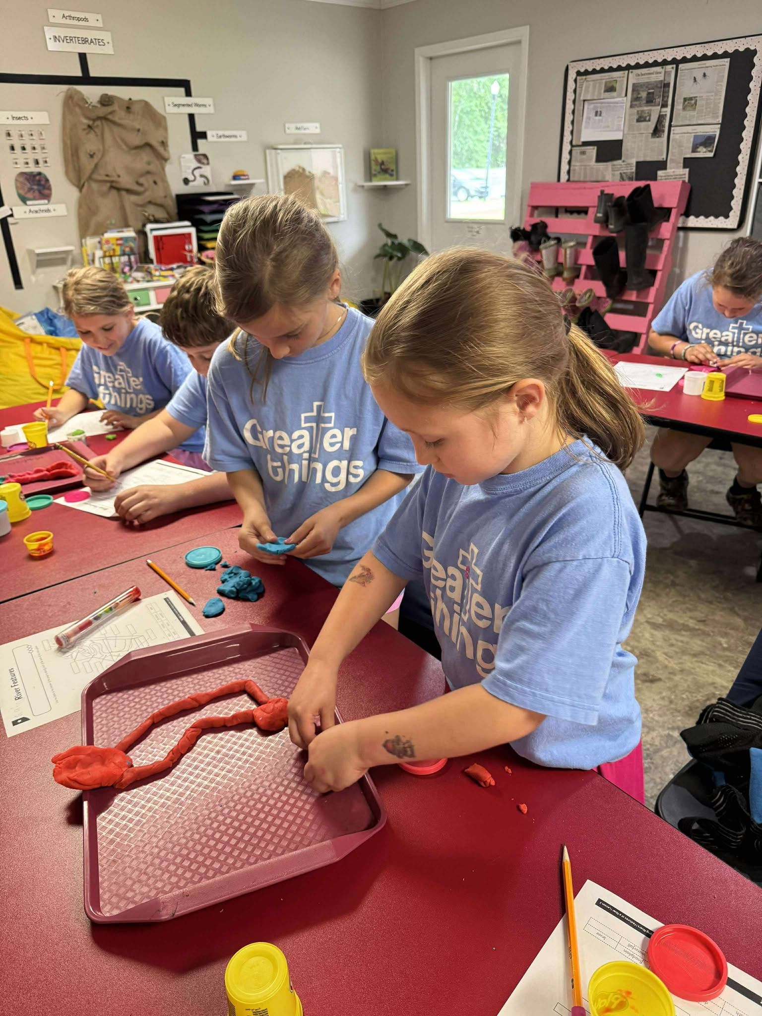 A group of children are sitting at a table playing with clay.