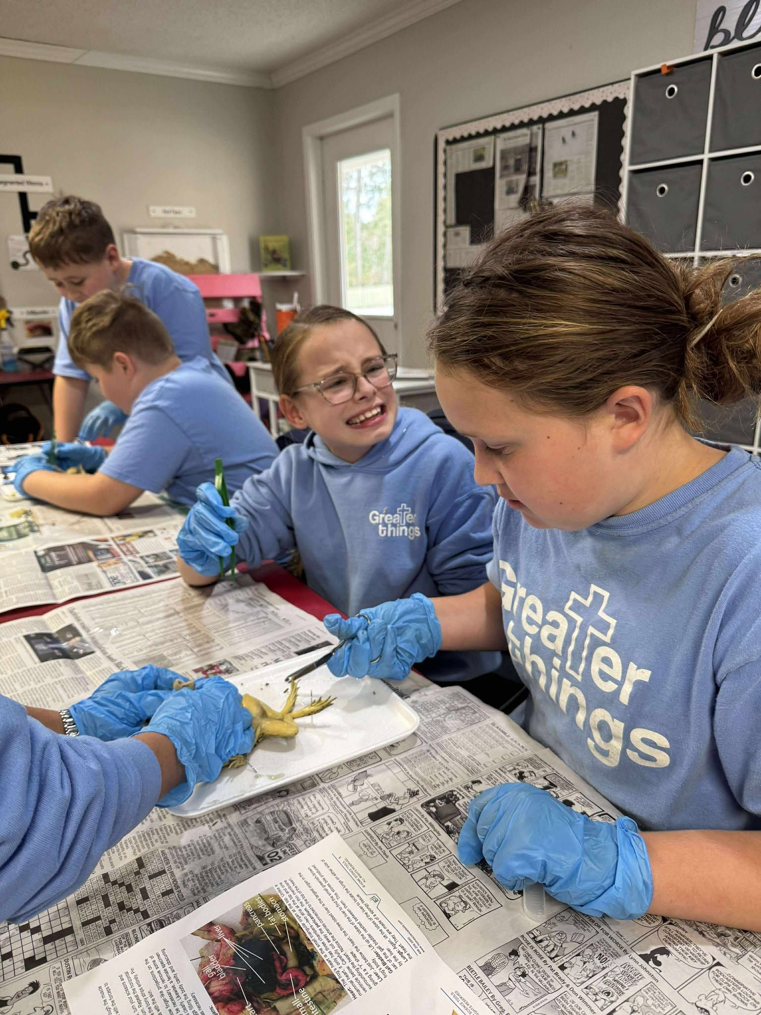 A group of children wearing blue gloves are sitting at a table.
