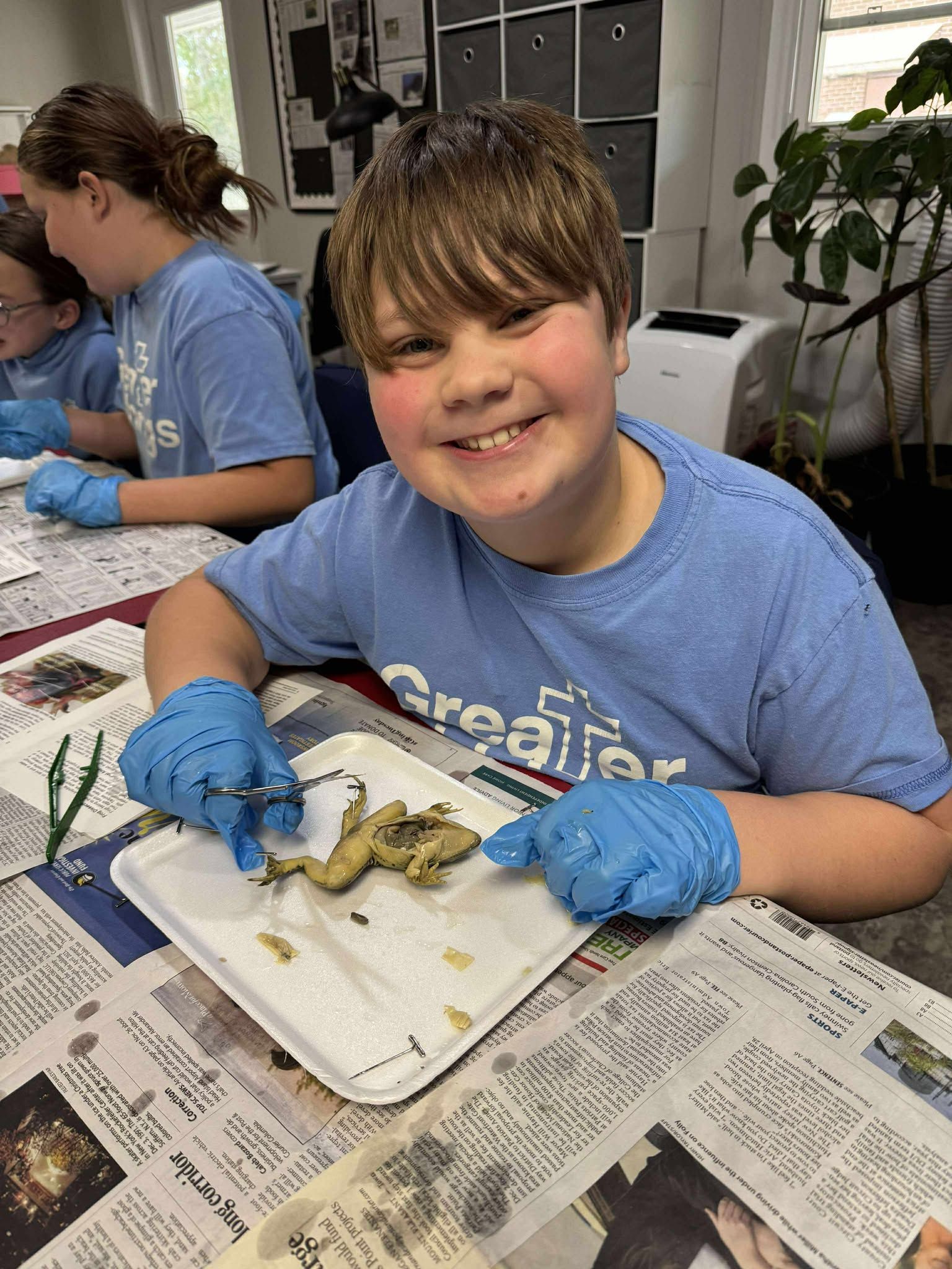 A young boy wearing blue gloves is sitting at a table with a plate of food.