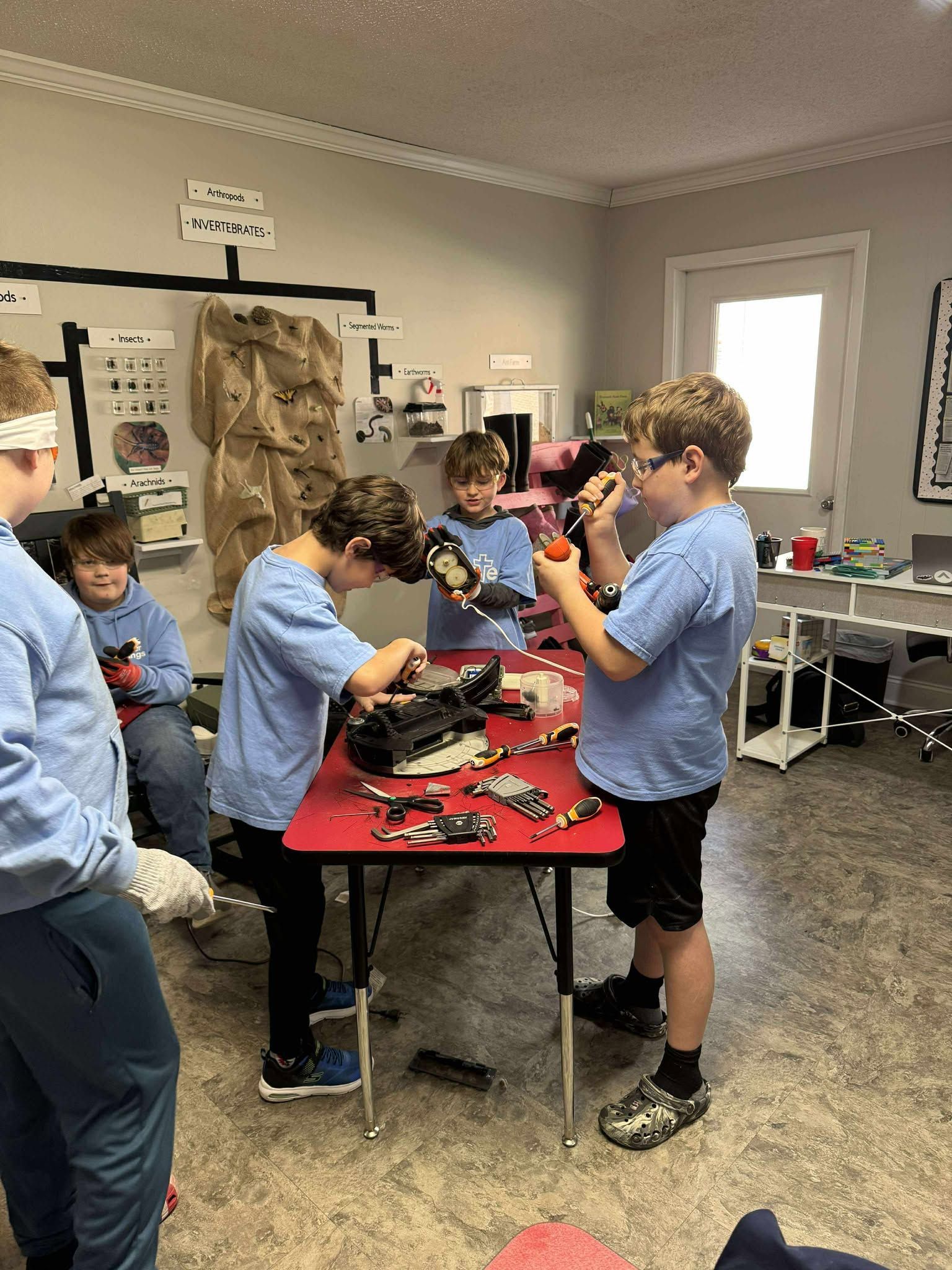 A group of young boys are working on a robot in a room.