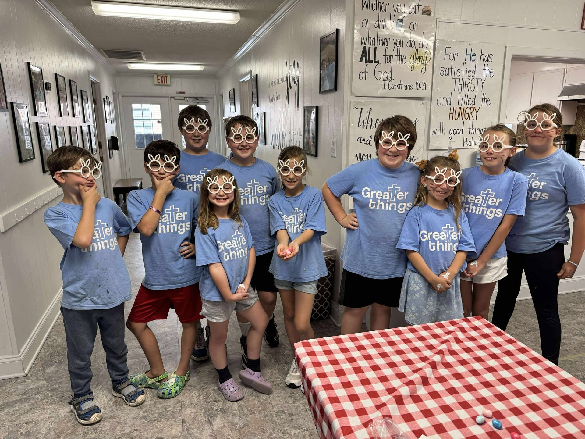 A group of children wearing blue shirts and glasses are posing for a picture.