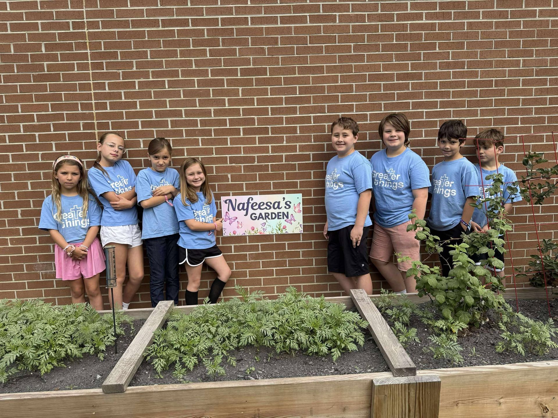 A group of children are standing in front of a brick wall.