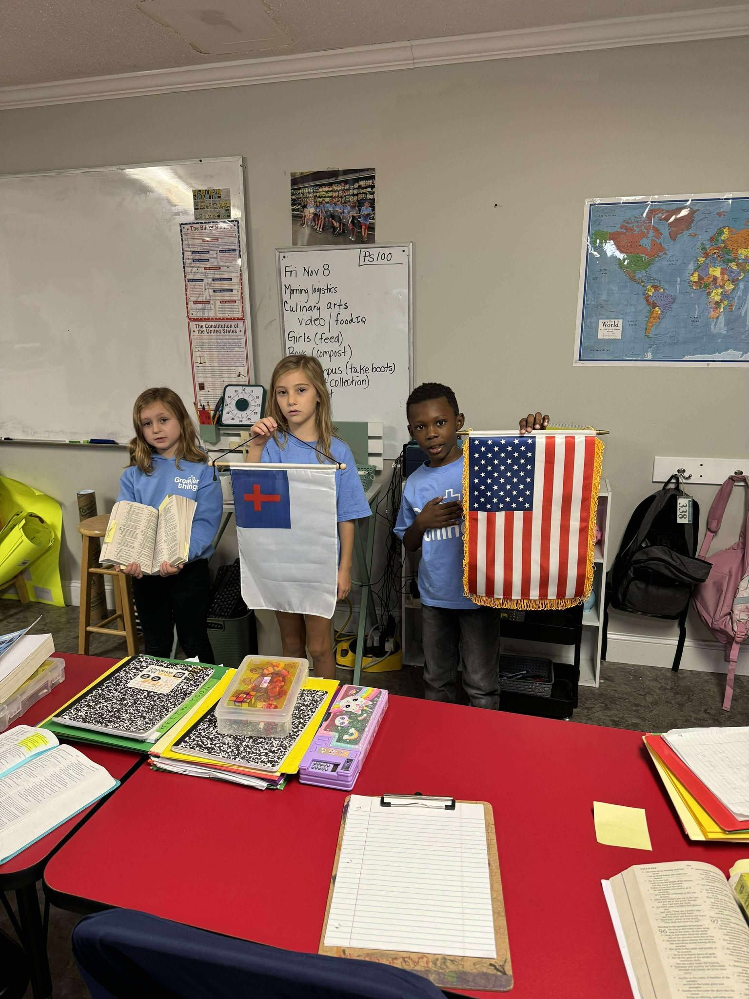 A group of children are standing in a classroom holding flags.