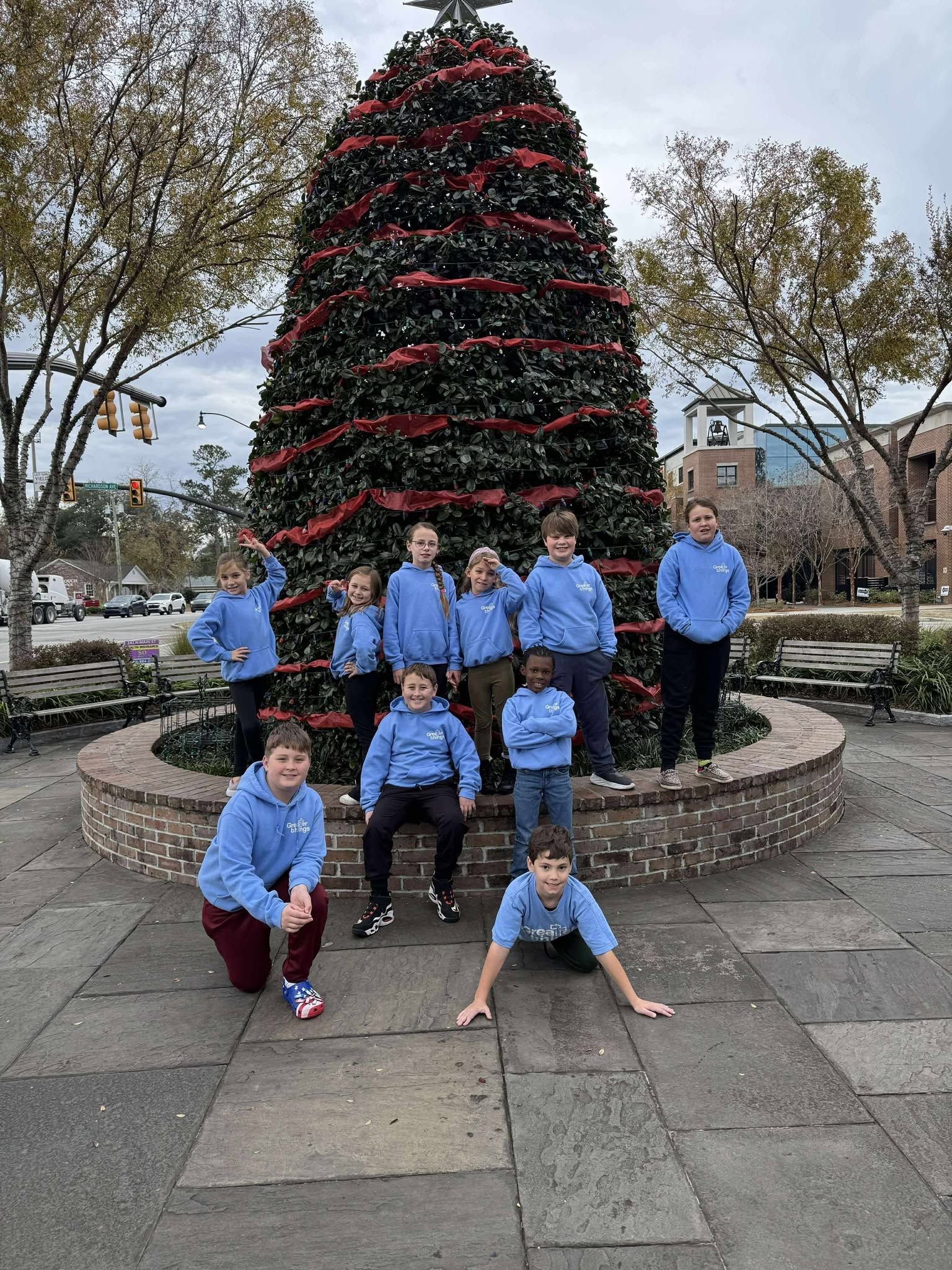 A group of children are posing for a picture in front of a christmas tree.