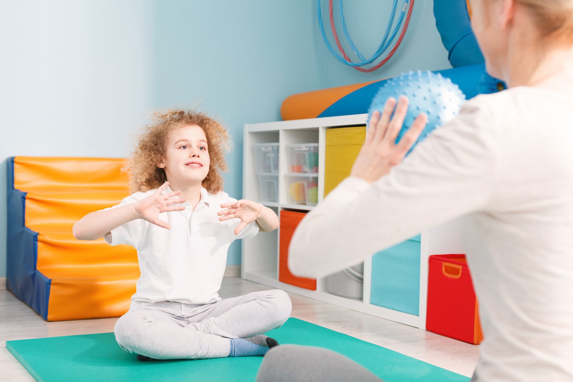 A woman is teaching a child how to play with a ball.