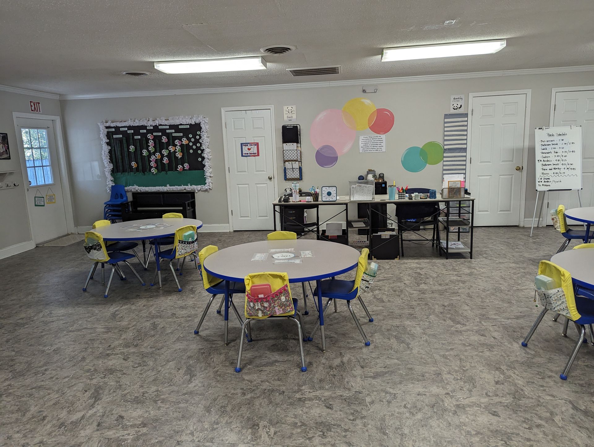 A classroom with tables and chairs and balloons on the wall.