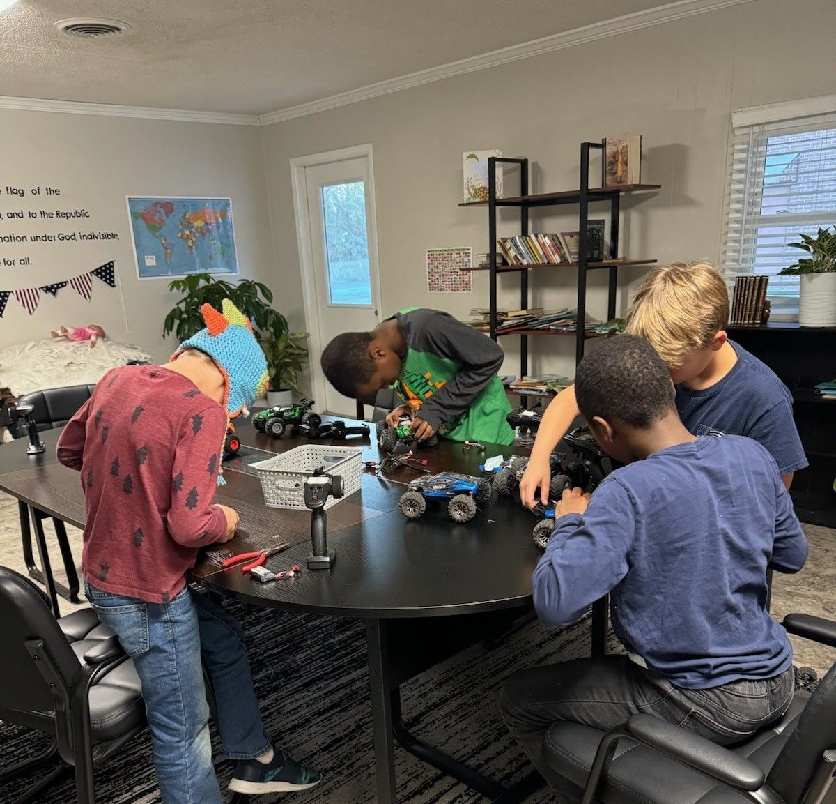 A group of young boys are sitting around a table playing with toys.