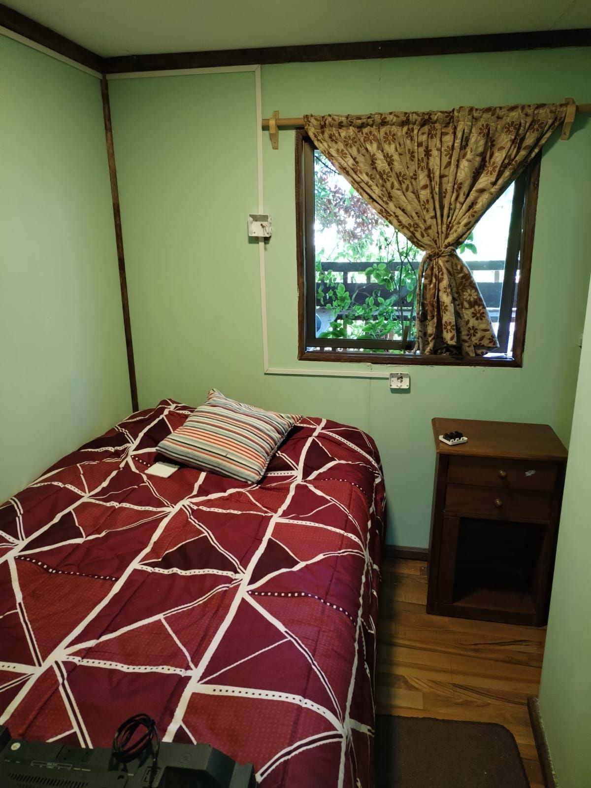 Un dormitorio con una cama, una mesita de noche y una ventana.