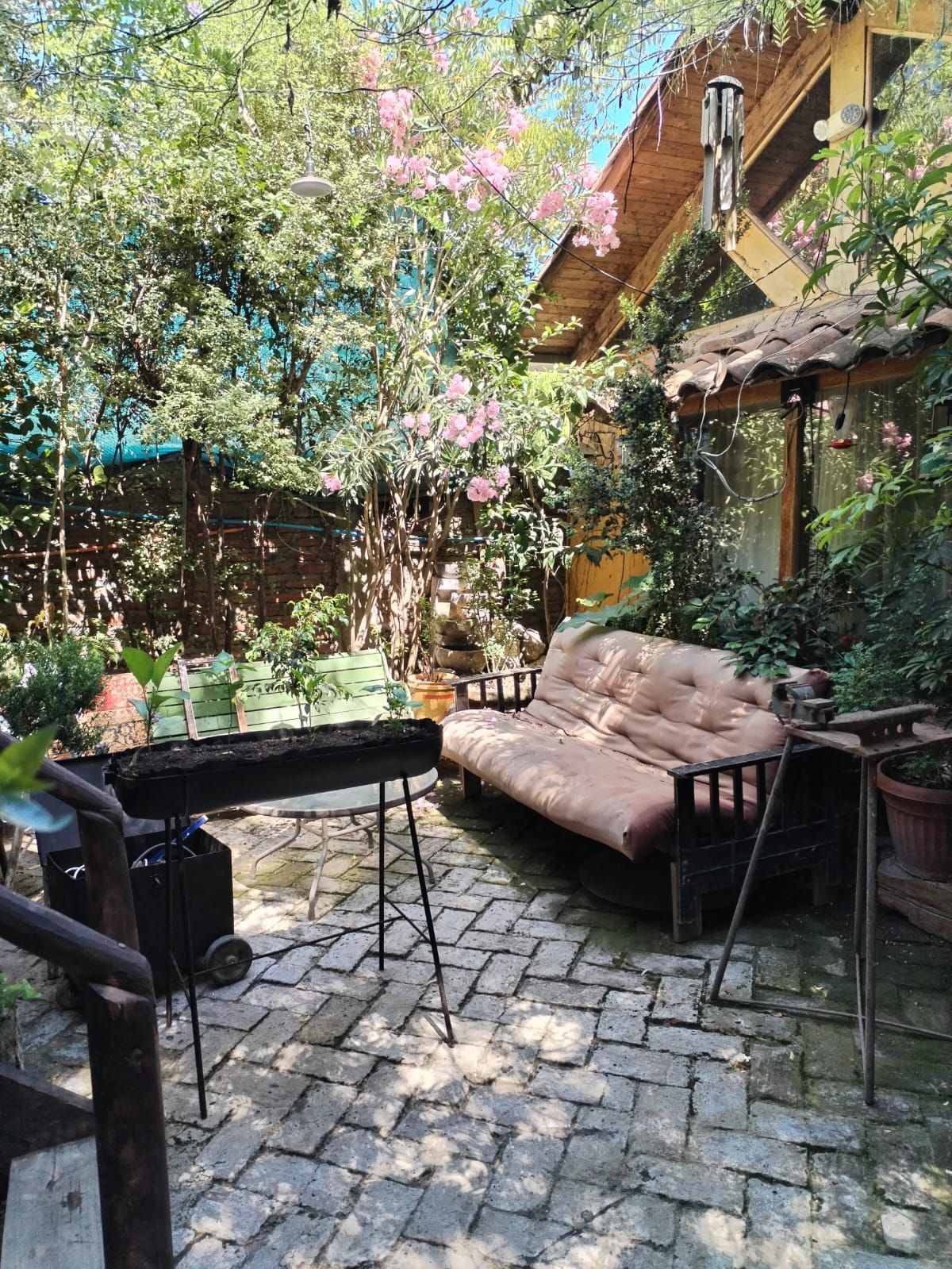 Un patio con sofá y parrilla en un jardín.