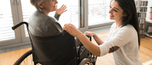 A woman is helping an elderly woman in a wheelchair.