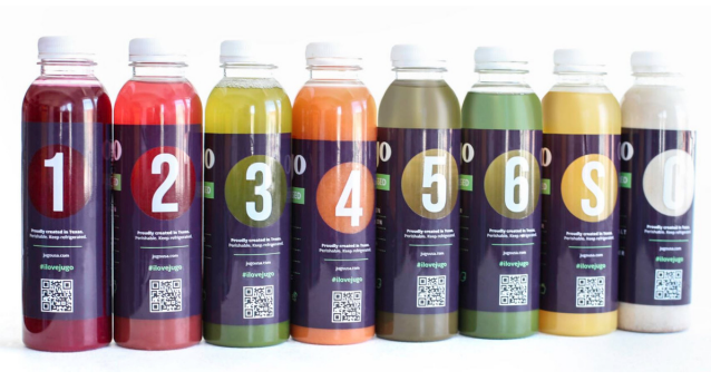 A row of bottles of juice are lined up in a row.