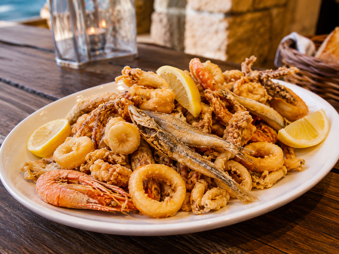 Piatto di frutti di mare fritti e spicchi di limone su un rustico tavolo di legno.