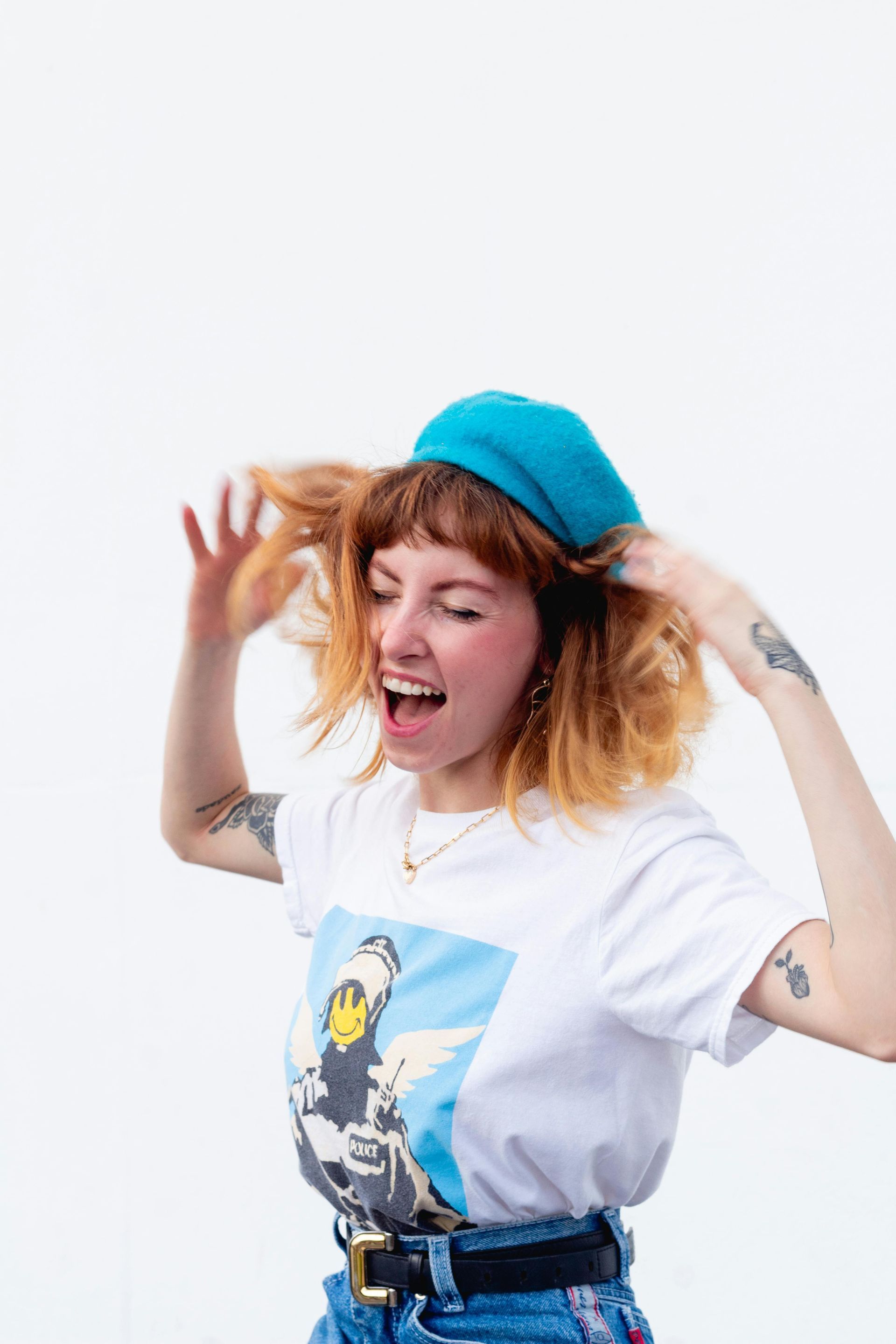 A woman wearing a blue hat and a white t-shirt is making a funny face.