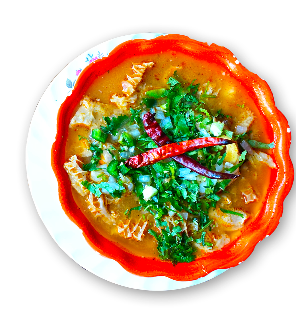 A bowl of soup with meat and vegetables on a white plate.