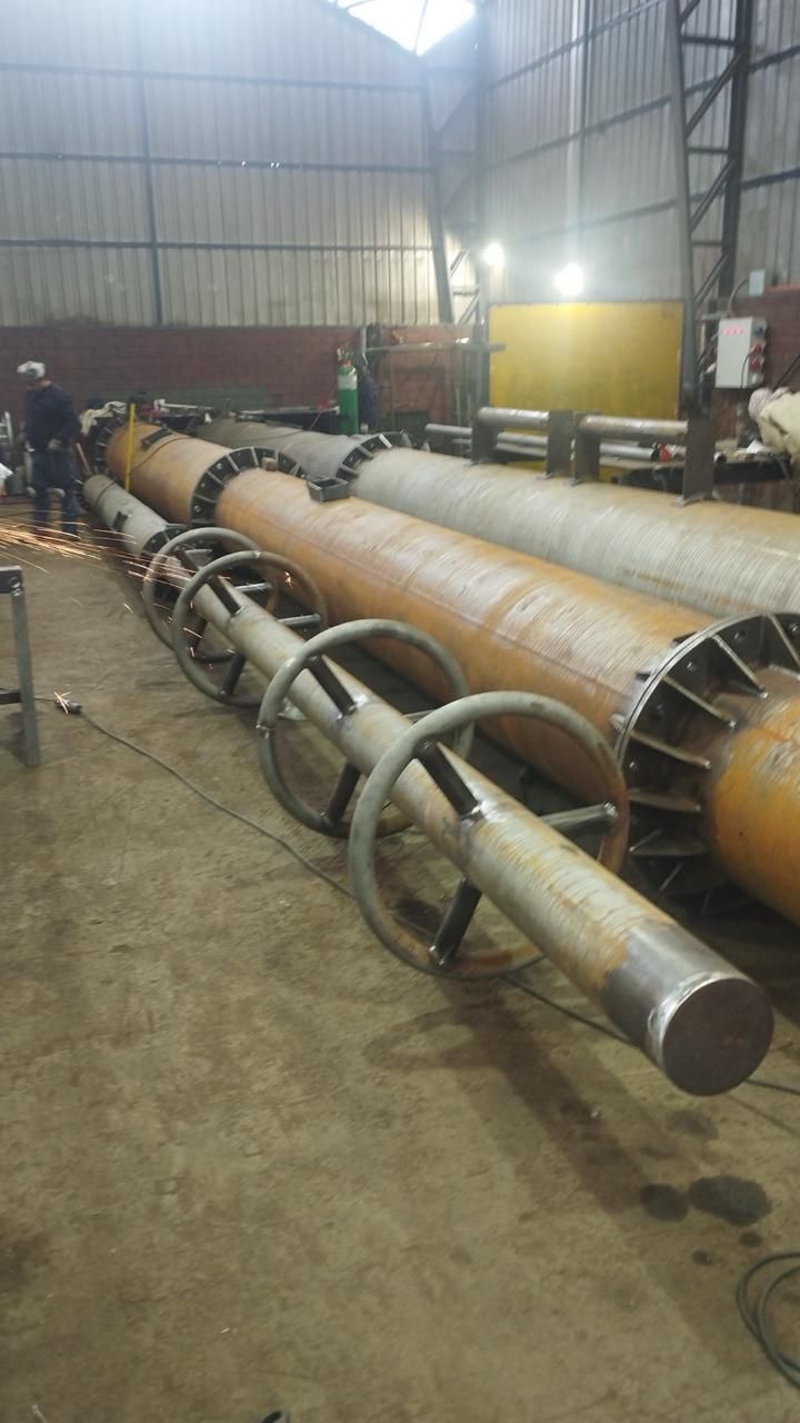 Tuberías metálicas en construcción en una fábrica. Un trabajador está soldando.