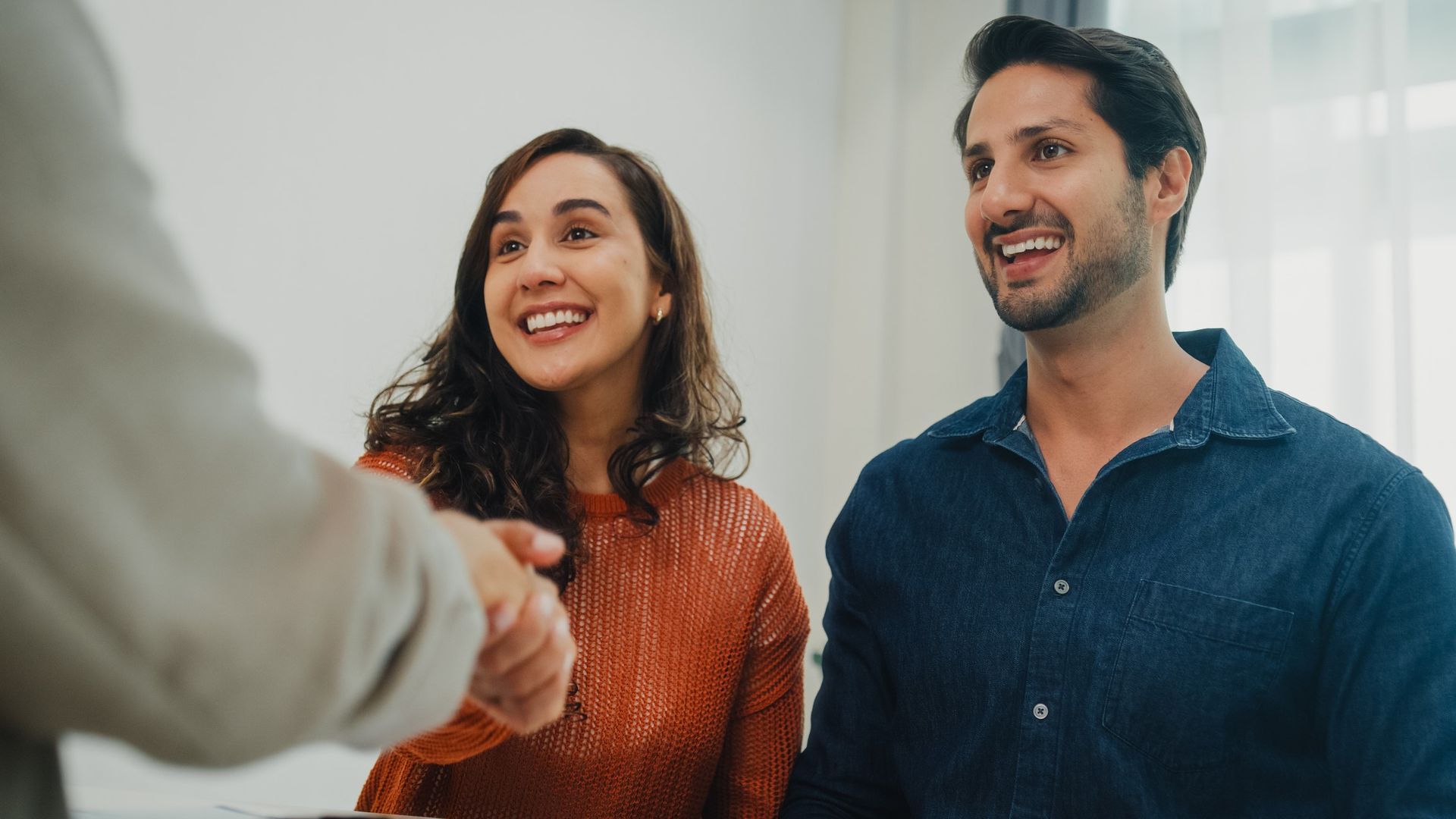 A man and a woman are shaking hands with a real estate agent.