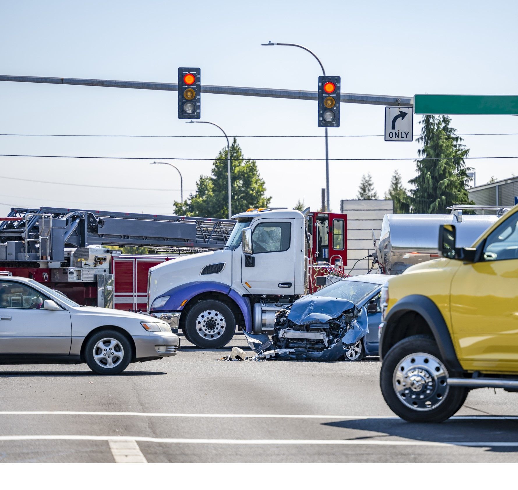 A yellow truck is driving down a street next to a white truck