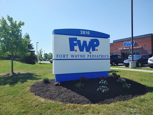 Fort Wayne Pediatrics sign with blue and white lettering beside a parking lot