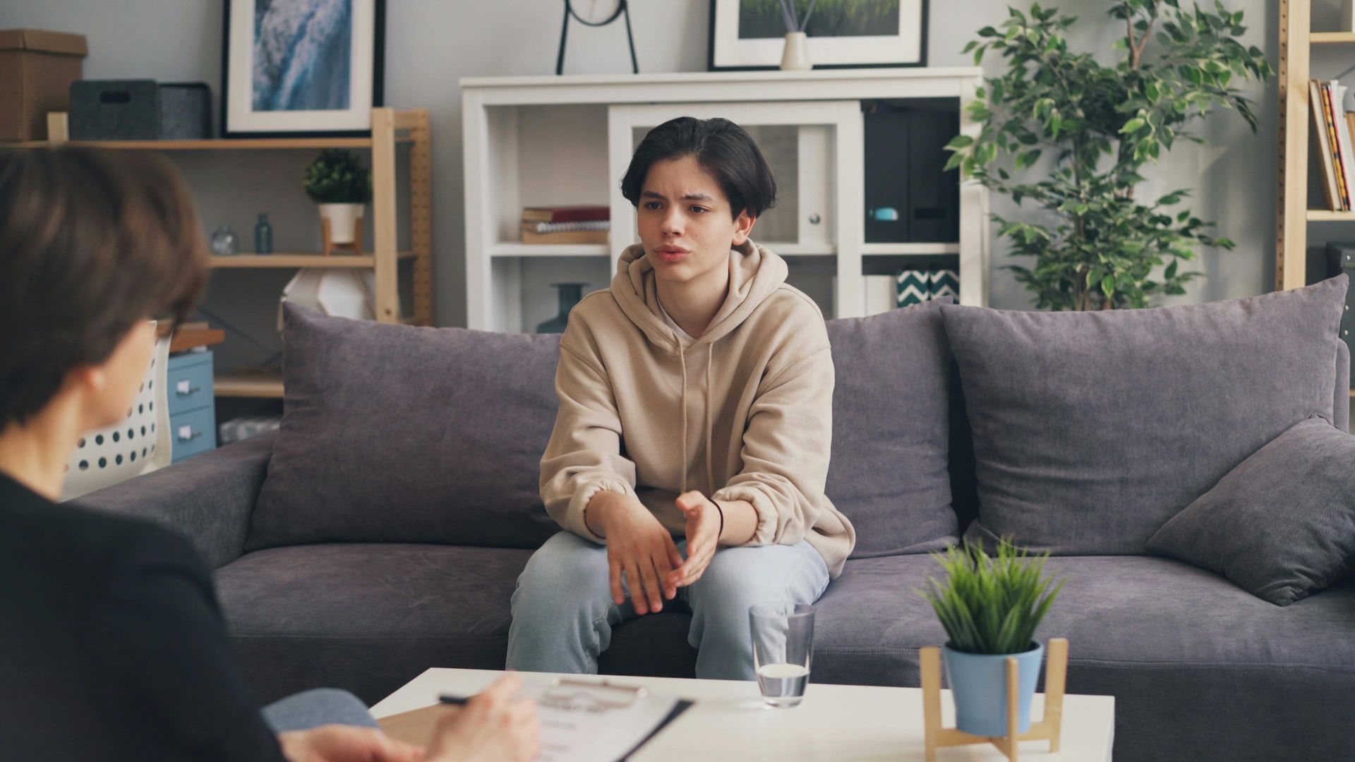 Person sitting on a gray couch in a living room during a counseling conversation