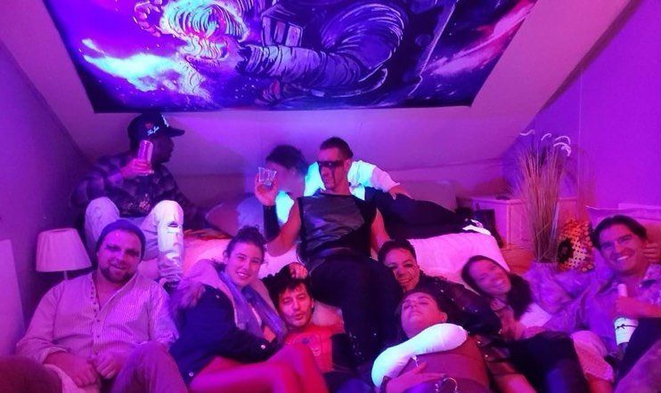 A group of people are posing for a picture in a room with purple lights.