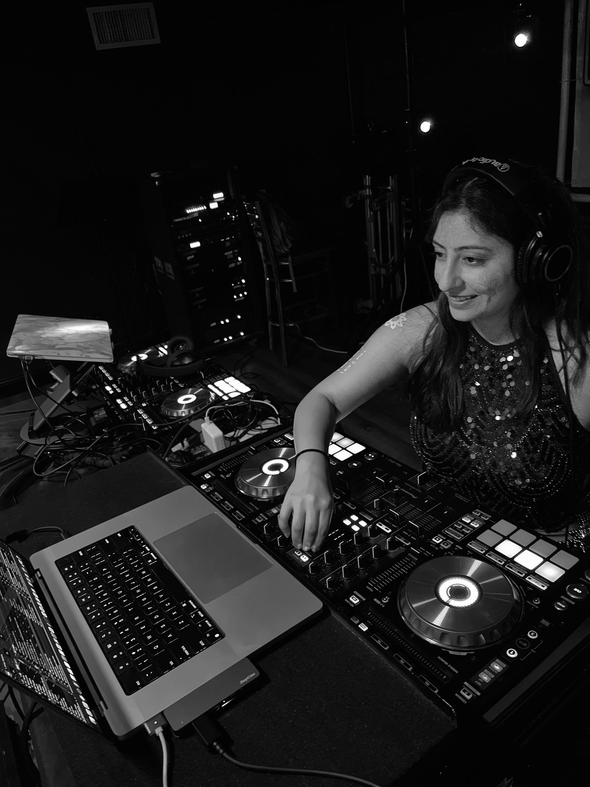 A woman is playing music on a laptop in a black and white photo.