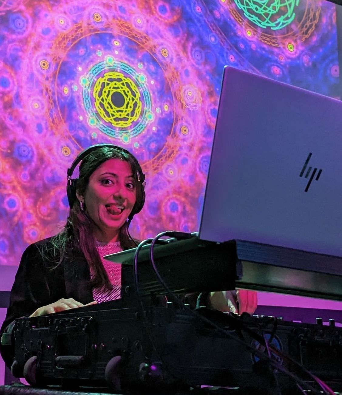 DJ Begum wearing Audio Technica headphones is sitting in front of a laptop computer.