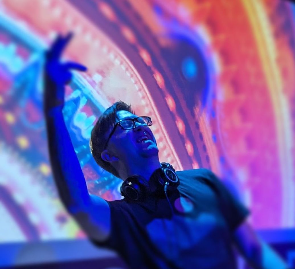 A man wearing headphones is dancing in front of a large screen