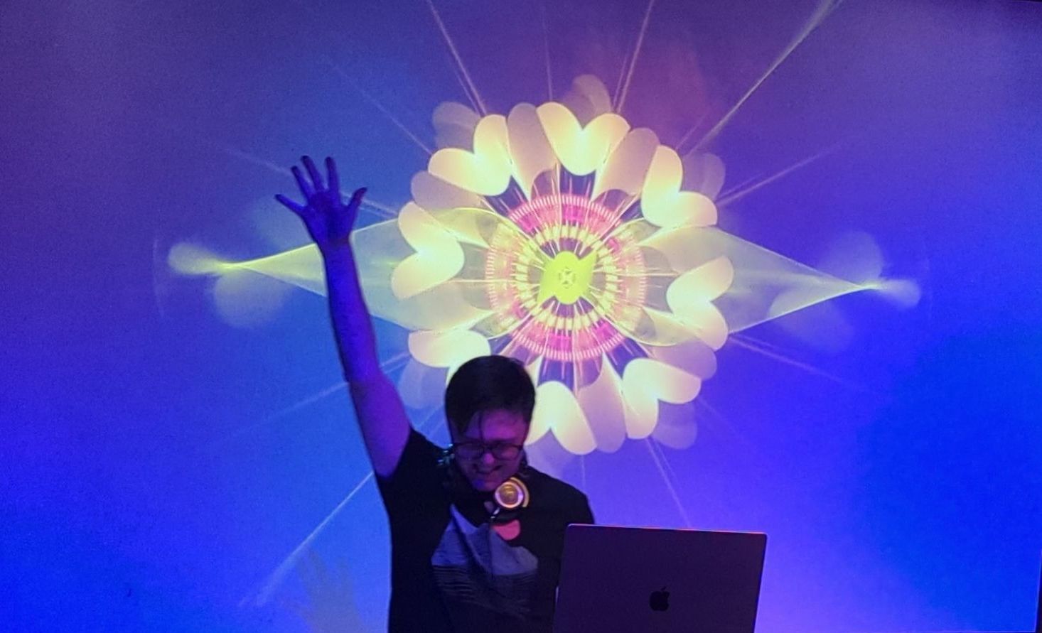 A man is standing in front of a laptop with his hand in the air.