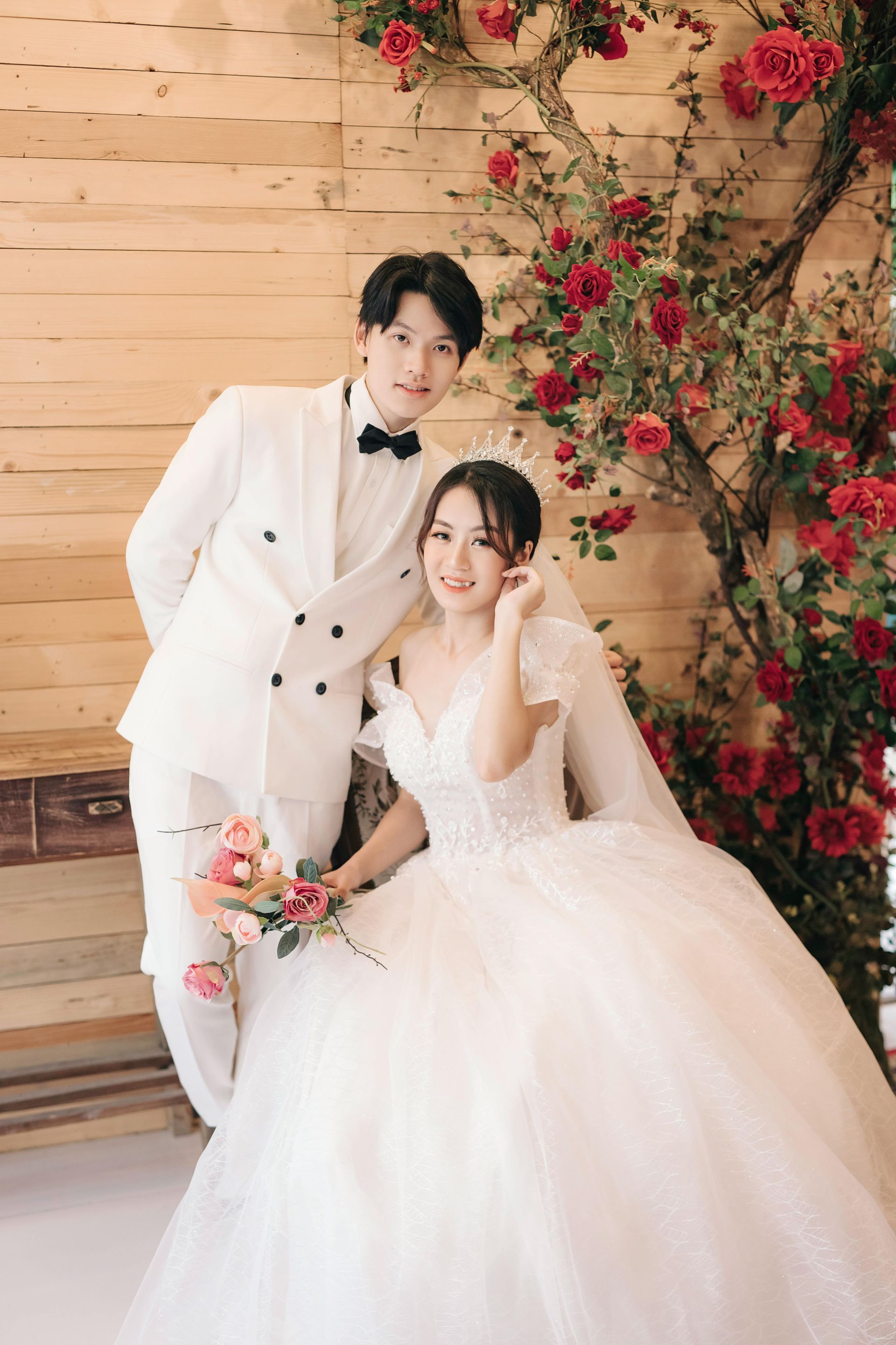 A bride in a veil is sitting in a car looking out the window.